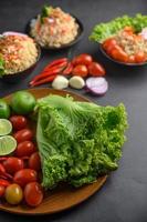 Lime slices, shallots, garlic, tomatoes, lettuce and peppers on a wooden plate photo