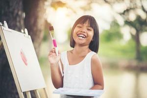 niña artista pintando un cuadro en el parque foto