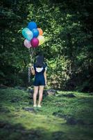 Young girl holding colorful balloons in nature photo