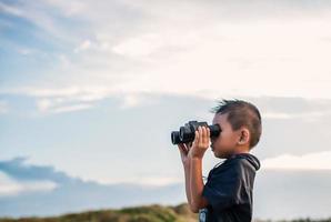 Niño feliz jugando con binoculares en la pradera foto
