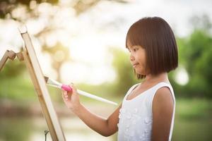 Little girl artist painting a picture in the park photo