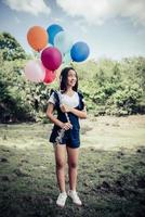 Young girl holding colorful balloons in nature photo