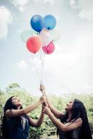 Grupo de novias felices sosteniendo globos multicolores en un parque foto