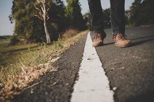 Close-up of young tourist man walking on a countryside road photo