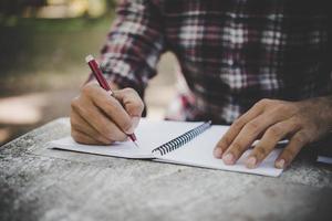 hombre escribiendo a mano en su cuaderno foto