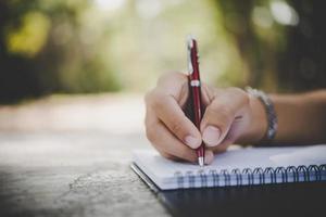 hombre escribiendo a mano en su cuaderno foto