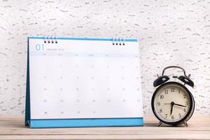 Alarm clock and calendar on wooden surface photo