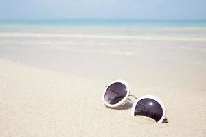 Sunglasses on sandy beach photo