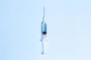 Syringe with blue liquid on blue background photo