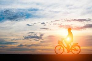 Young man rides a bicycle on sunset background
