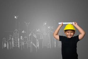 Young boy wearing a yellow engineer hat and house plan ideas on a blackboard photo