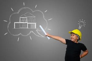 Joven con un sombrero de ingeniero amarillo e ideas del plan de la casa en una pizarra foto