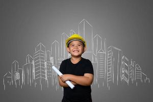 Joven con un sombrero de ingeniero amarillo e ideas del plan de la casa en una pizarra foto