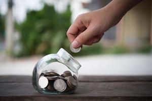 Hands putting money into bottle for cash in the future photo