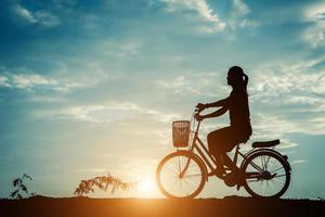 silueta de una mujer con una bicicleta y un hermoso cielo foto