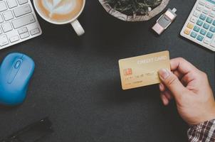 vista superior de alguien sosteniendo una tarjeta de crédito en un escritorio foto