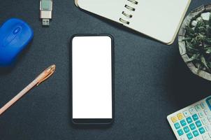 vista superior del teléfono, el cuaderno y el bolígrafo en un escritorio foto