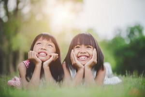 Little girls lying comfortably on the grass and smiling photo