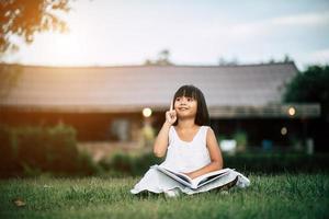 niña leyendo un libro en el jardín de su casa afuera foto