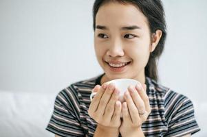 mujer joven, tenencia, un, taza de café, en cama foto