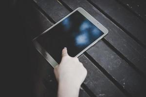 Close-up of a woman hand using a tablet computer on wooden table photo