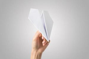 Woman's hand holding a paper airplane isolated on white background photo
