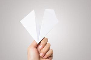 Woman's hand holding a paper airplane isolated on white background photo