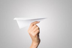 Woman's hand holding a paper airplane isolated on white background photo