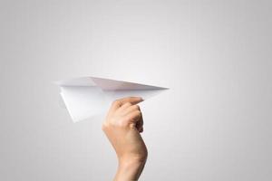 Woman's hand holding a paper airplane isolated on white background photo