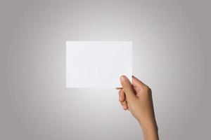 Close-up de la mano de una mujer sosteniendo papel en blanco aislado sobre fondo blanco. foto