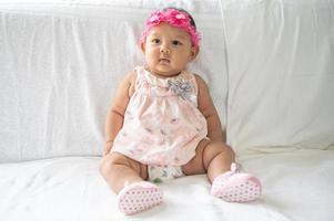 A baby learning to sit on a white bed photo