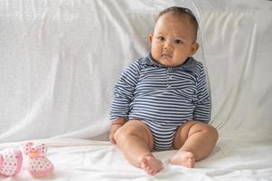 A baby learning to sit on a white bed photo