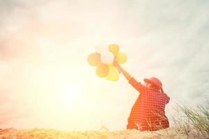 Young hipster woman holding balloons below the sky photo