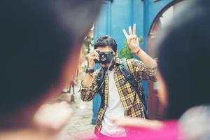 Young man taking pics of his friends while traveling in urban area together photo