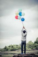 Young man holding colorful balloons in nature photo