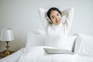 mujer joven, estirar cama, con, computador portatil