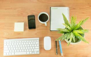 Flat lay of desk with plant, coffee, and phone photo