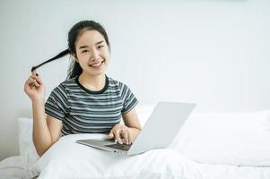 mujer joven, juego, en, ella, computadora portátil, en cama foto