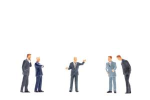 Miniature figurines of business people standing on white background