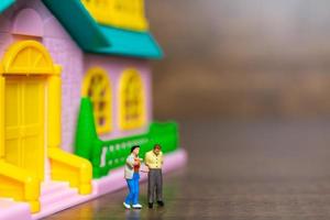 Two miniature figurines in front of a pink house photo