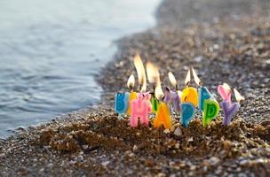 velas de cumpleaños ardiendo en una orilla del mar