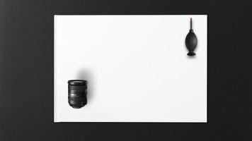 Lente de la cámara y soplador de aire sobre papel blanco y fondo negro foto