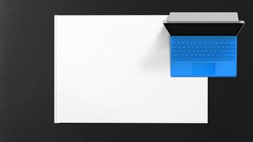 Blue laptop on white paper on black background photo