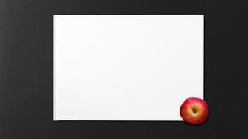 Red apple on white paper on black background