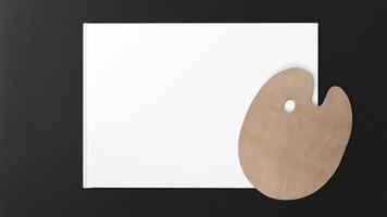 Wooden artist palette on white paper and black background photo