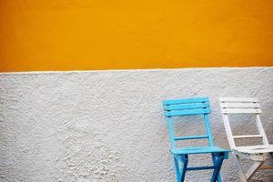 Blue and white wooden chairs against gray and orange wall photo