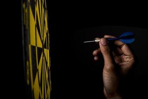 Dartboard with arrow on black background, success concept photo