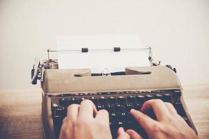 Hands typing on vintage typewriter on wooden table photo