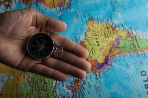 Man holding a compass on top of a map photo