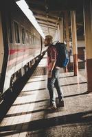 Turista joven inconformista con mochila en la estación de tren